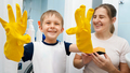 SMiling toddler boy wearing yellow rubber gloves laughing while doing housework and home cleanup - PhotoDune Item for Sale
