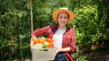 Happy farmer or gardener holding box full of fresh ripe vegetables in garden - PhotoDune Item for Sale