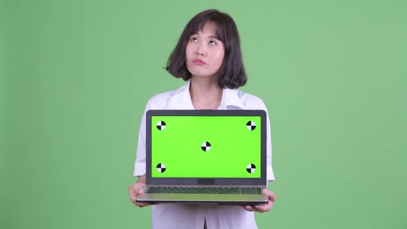 Happy Beautiful Asian Businesswoman Thinking While Showing Laptop