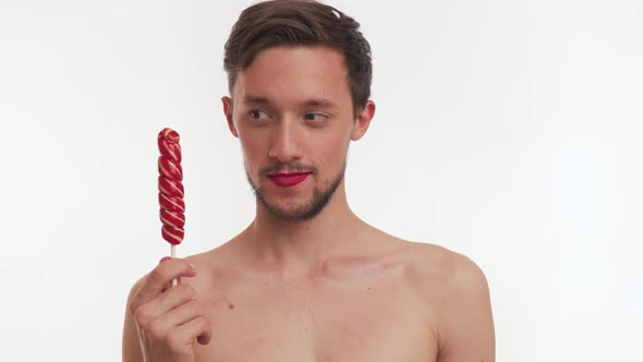 Half naked bearded man hold sweet lollipop, look camera, awkwardly hints for date, flirt, smile