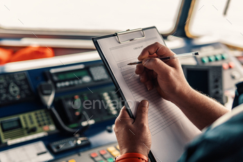 ation watch on ship or vessel. He fills up checklist. Ship routine paperwork