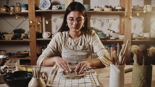 Young Woman Potter Makes Patterns of the Piece of Clay Using Stamping