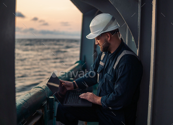 Marine chief officer or captain on deck of vessel or ship watching laptop / Photodune, Misc