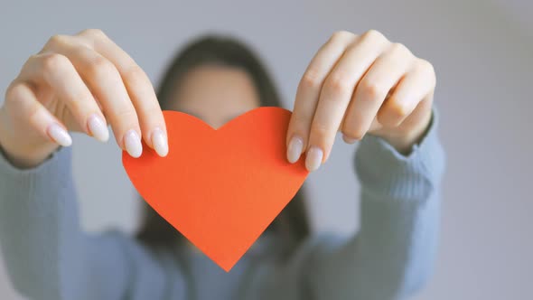 Pretty Young Brunette Female Tearing Red Paper Heart on Camera Broken Heart