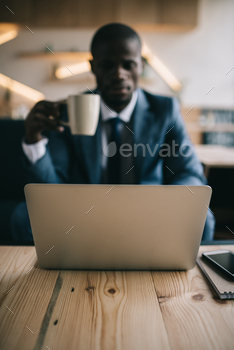 selective focus of african american businessman working with laptop during coffee break in cafe / Photodune, Misc