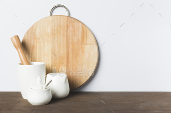 close-up view of ceramic kitchenware, wooden pestle and cutting board on table / Photodune, Misc