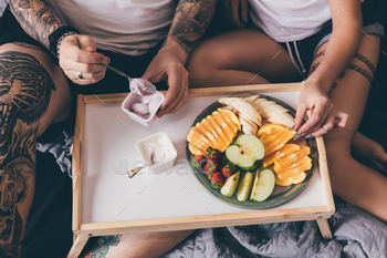 overhead view of couple having breakfast with yogurts and fruits together in bed in morning / Photodune, Misc