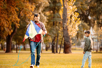 Father and son playing with kite in an autumn park / Photodune, Misc