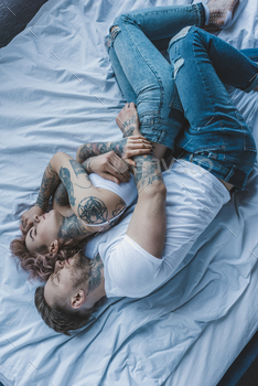top view of tattooed couple hugging and sleeping on bed / Photodune, Misc