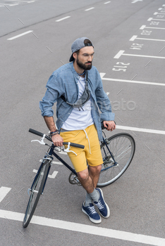 high angle view of hipster man sitting on bicycle on street / Photodune, Misc