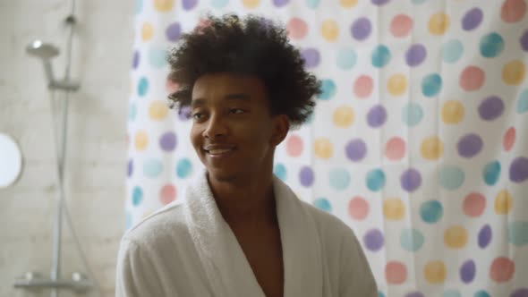 Young Black Man Touching Face Looking in Mirror Smiling To His Reflection Standing in Bathroom