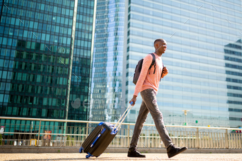 Full body side of young black man walking with suitcase in city / Photodune, Misc