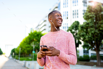 Horizontal portrait smiling young black man listening to music with cellphone and earphones / Photodune, Misc