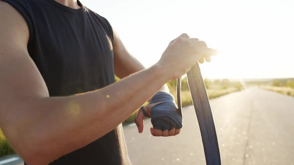 Close View of Athlete in Sportswear Wrapping Hand Into Tape at Camera on Nature