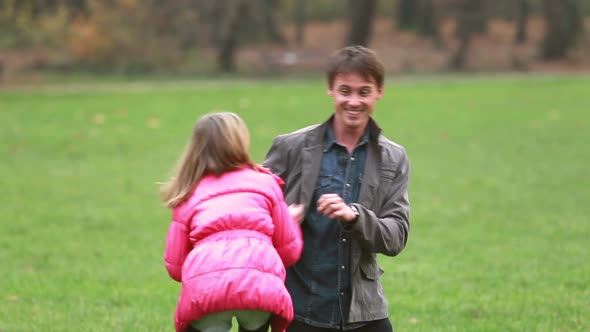Young dad playing with daughter in park