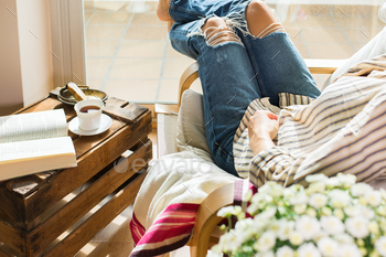 Young woman is relaxing at home, drinking tea, reading book / Photodune, Misc