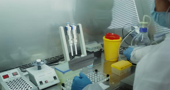 A Female Laboratory Assistant in Sterile Disposable Clothing Checks Blood Tests