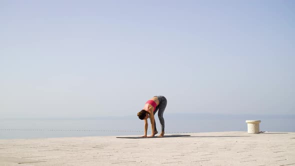 Yoga Training by Adult Woman on Empty Dock With Sea and Sky on Background