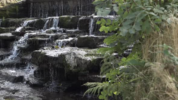 Water flowing over cascading waterfall medium panning shot