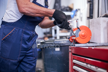 Mechanic using grinding machine at auto repair shop / Photodune, Misc