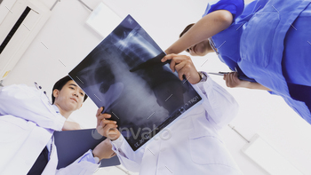 Doctor and medical assistants discussing about diagnosis result on x-ray film. / Photodune, Misc