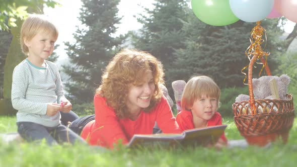 Mom and Funny Daughter Reading a Book Together, in the Park