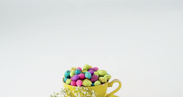 Cup filled with painted chocolate Easter eggs and white flower