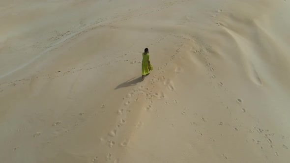 Aerial View of Woman Walking on Sand Dune