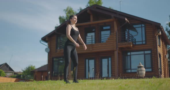 Young Athletic Girl Performs Squat Exercises Outdoors on Plot of Country House