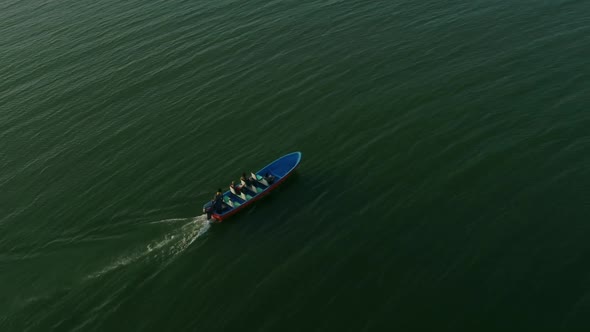 Aerial shot of a speed boat At Keenjhar Lake In Thatta, Pakistan at sunset with tourist.