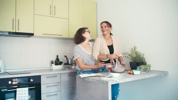 Lesbian Couple Dancing and Drinking Wine While Cooking Together
