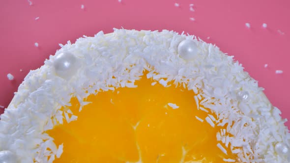 Cake with Orange and Coconut Shavings Spun on a Pink Background