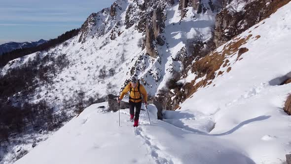 Hiker walking through snow in mountains, looking at view