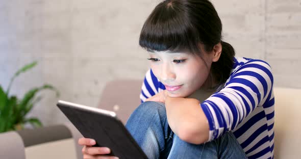 Woman watching on tablet computer at home