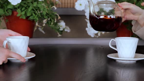 Pouring Red Tea Into a White Cup on a Wooden Table