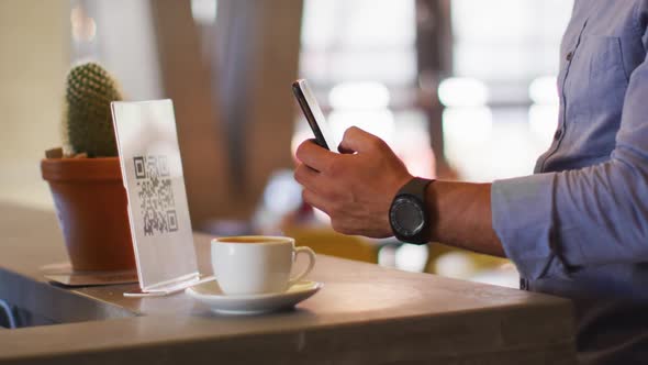 Mixed race man giving african american female cafe worker his smartphone in order to pay