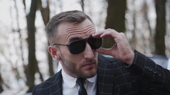 Gentleman Puts on Sunglasses Corrects Suit and Looks Around