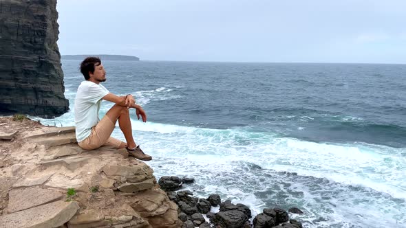 A Young Man on a Hike Among Rocks Near the Sea