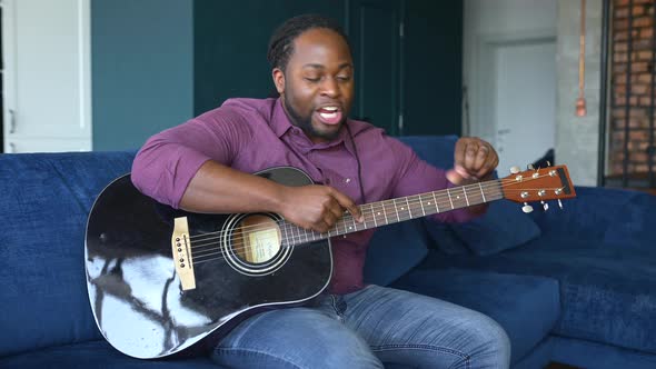 Headshot of Happy AfricanAmerican Musician Tutor Playing Guitar