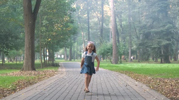 Little child girl playing with a white dog on a street. alt