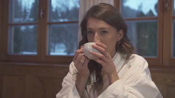 A woman drinking tea in a hotel room at a ski resort