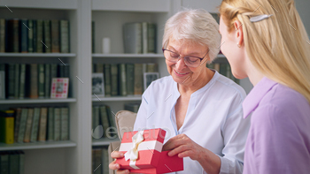 Young daughter giving a gift to an elderly mother for mother's day / Photodune, Misc