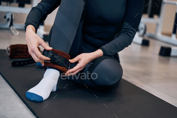 Pretty caucasian woman in black sportwear wearing cuffs of ankle support. Protection and anti-sprain / Photodune, Misc