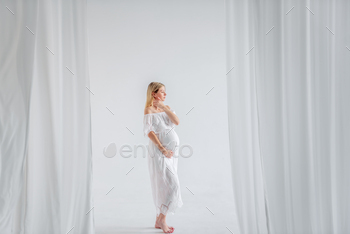 Young pregnant woman in anticipation of baby in white dress, hugs belly. Fashion girl copy space / Photodune, Misc