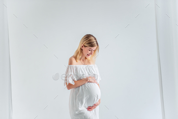 Young pregnant woman in anticipation of baby in white dress, hugs belly. Fashion girl copy space / Photodune, Misc