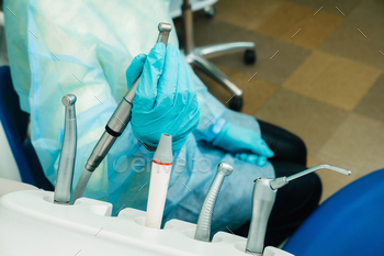 a dentist wearing gloves in the dental office holds a tool before working / Photodune, Misc