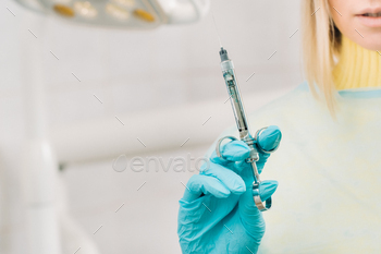 close-up of a dentist's hand holding an injection syringe for a patient in the office / Photodune, Misc