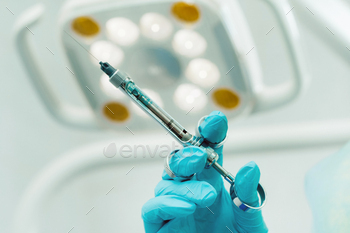 close-up of a dentist's hand holding an injection syringe for a patient in the office / Photodune, Misc