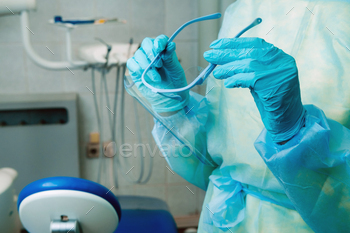 close up of a dentist's hands holding a protective plastic screen in his office / Photodune, Misc