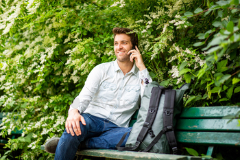 smiling man sitting in park talking with mobile phone / Photodune, Misc